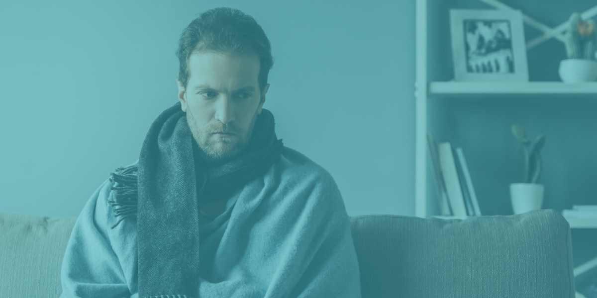 Worried man wrapped in a blanket, possibly ill.