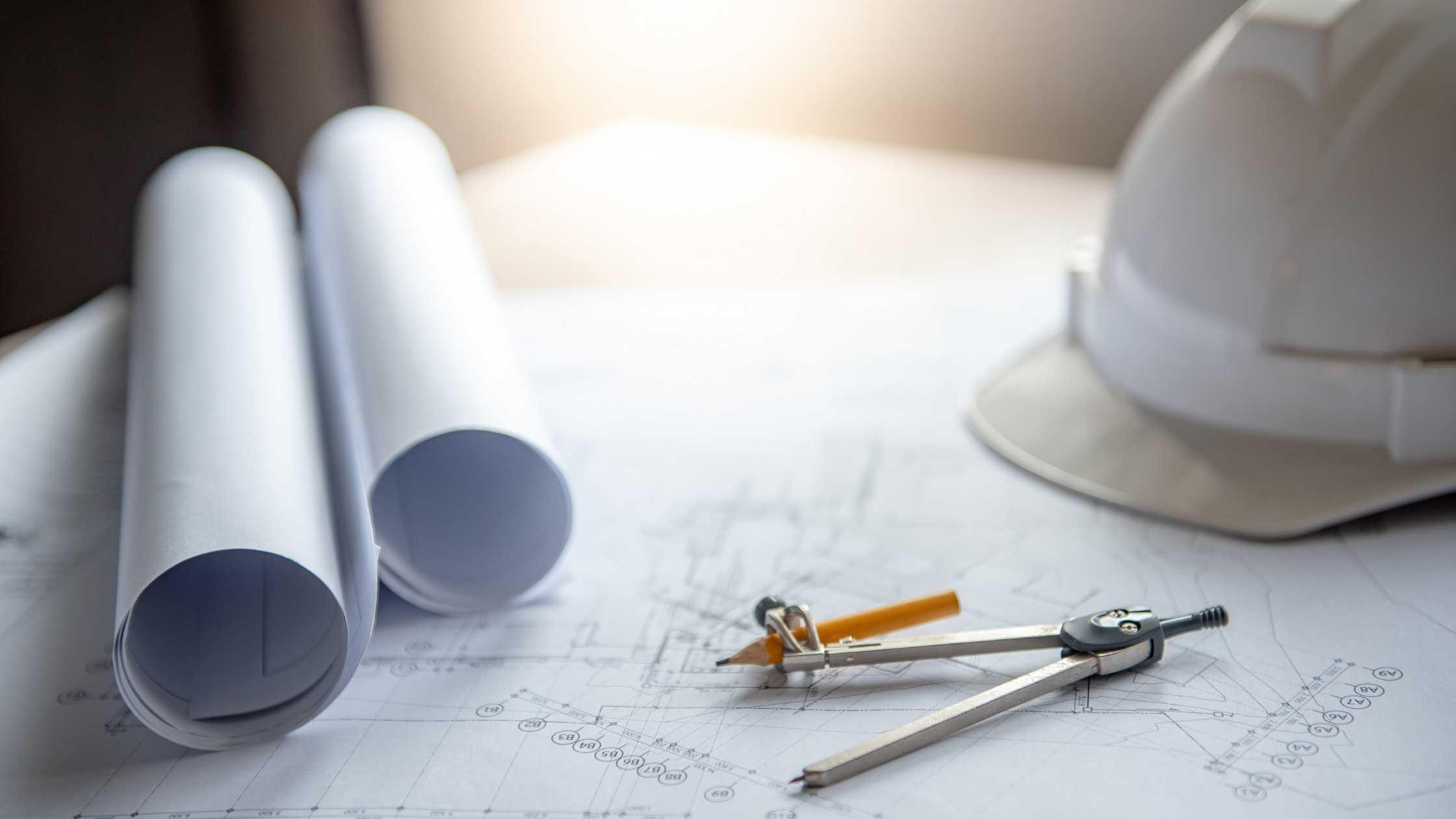 Architectural blueprints, compass, pencil, and hard hat; crucial project components.