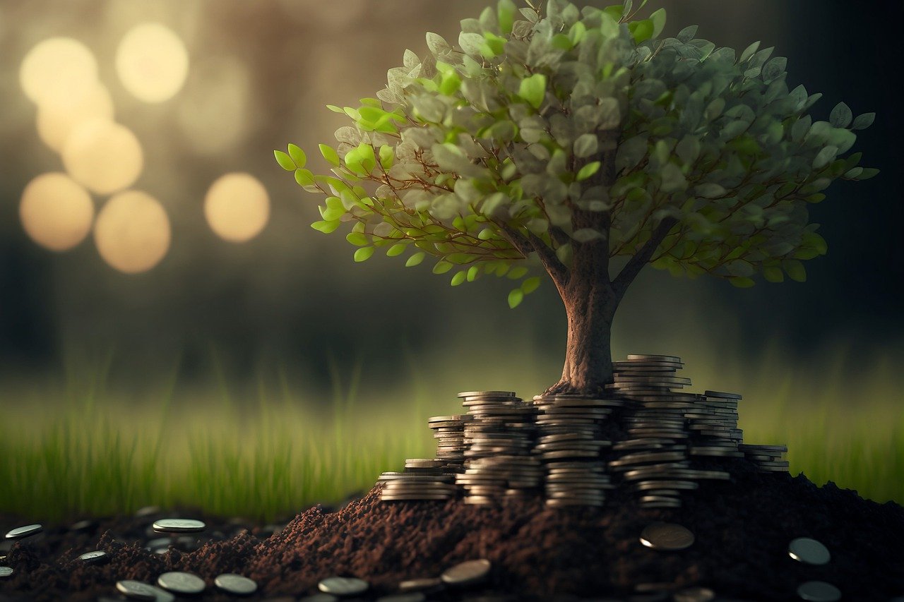A small tree grows from a mound of soil and coins, symbolizing financial growth and investment in a natural setting.