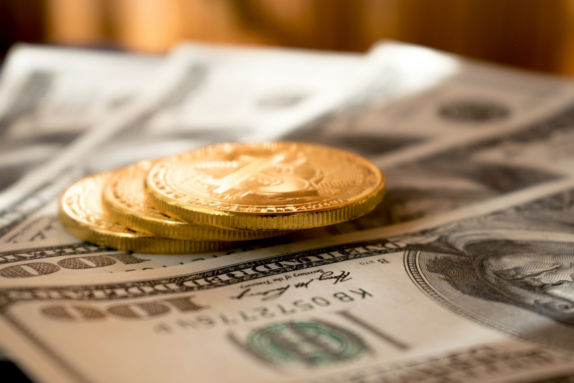 Gold Bitcoin coins on US dollar bills. International estate planning.