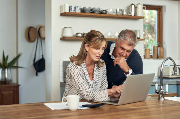 Couple reviewing documents and using laptop, planning international estate and superannuation.