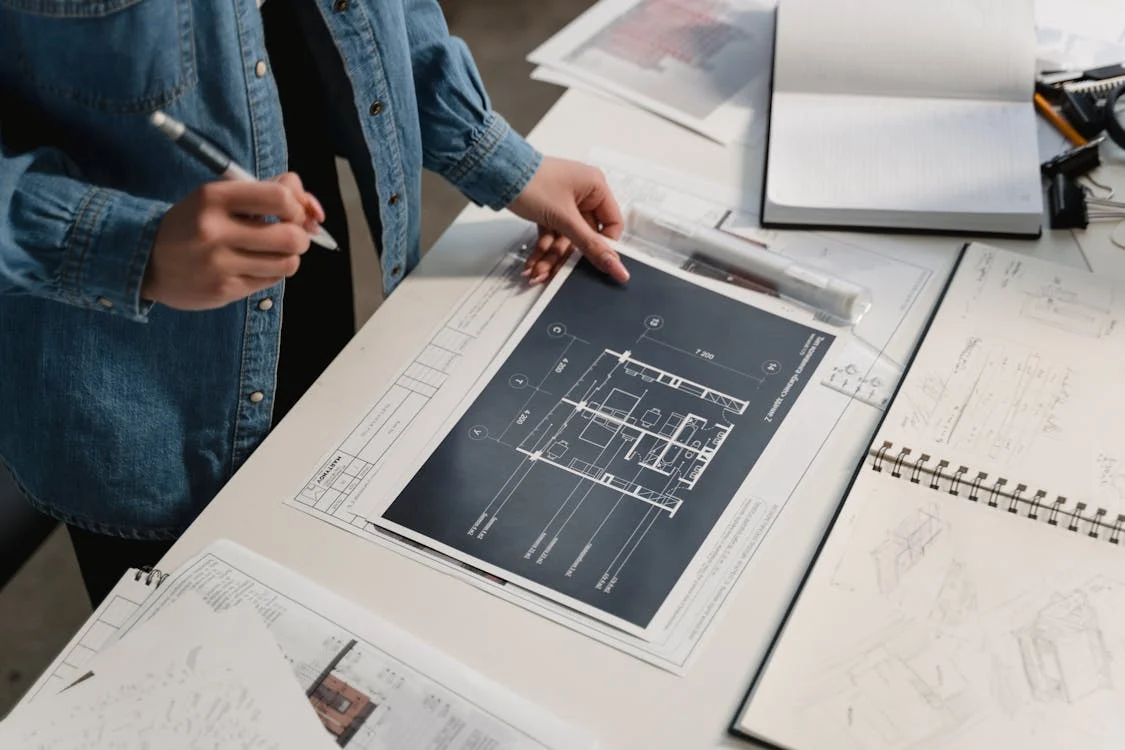 Person examining architectural plans for a guide on documenting building defects in NSW for owners corporations.