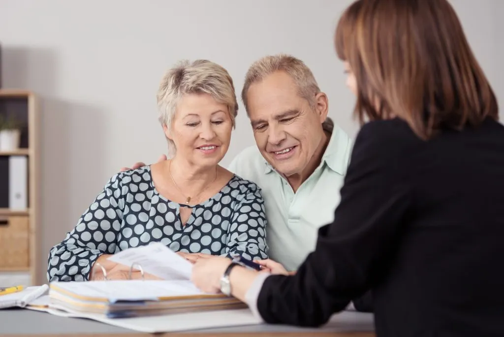 Couple discussing revocable living trusts pros and cons with an advisor, reviewing documents at a desk.