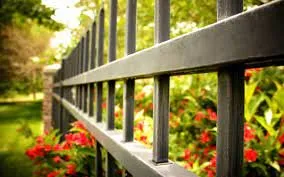 Close-up of a metal fence with greenery, illustrating the topic of who pays for dividing fence repairs in strata.
