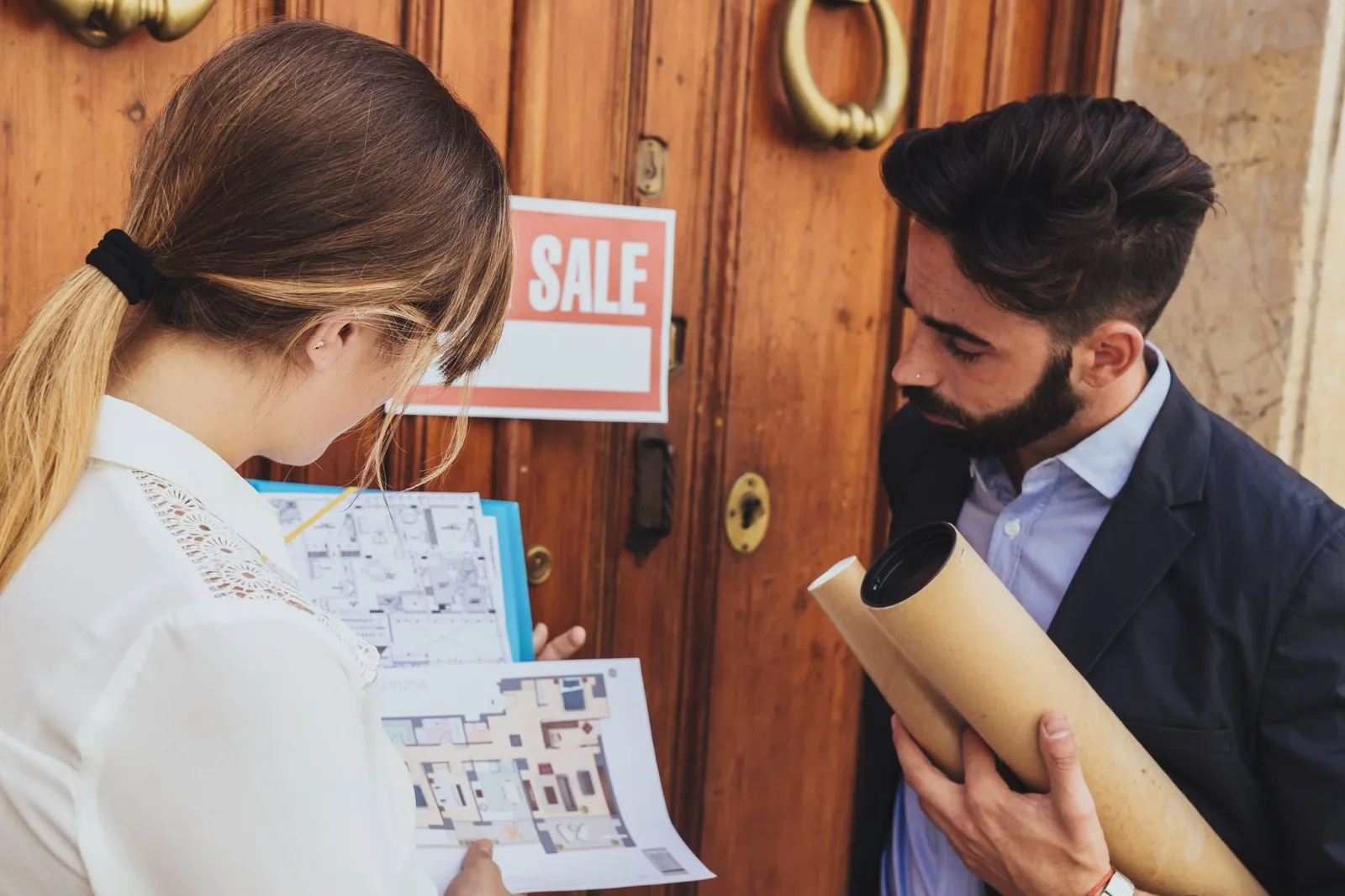 Two people review estate plans outside a home with a 
