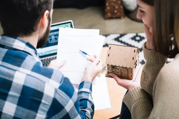Couple reviewing NSW estate property documents and a house model.
