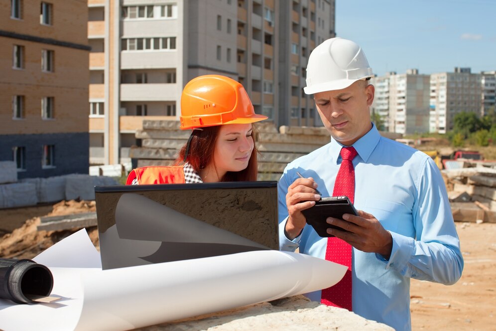 Construction professionals reviewing plans at a building site. Principal contractor obligations.