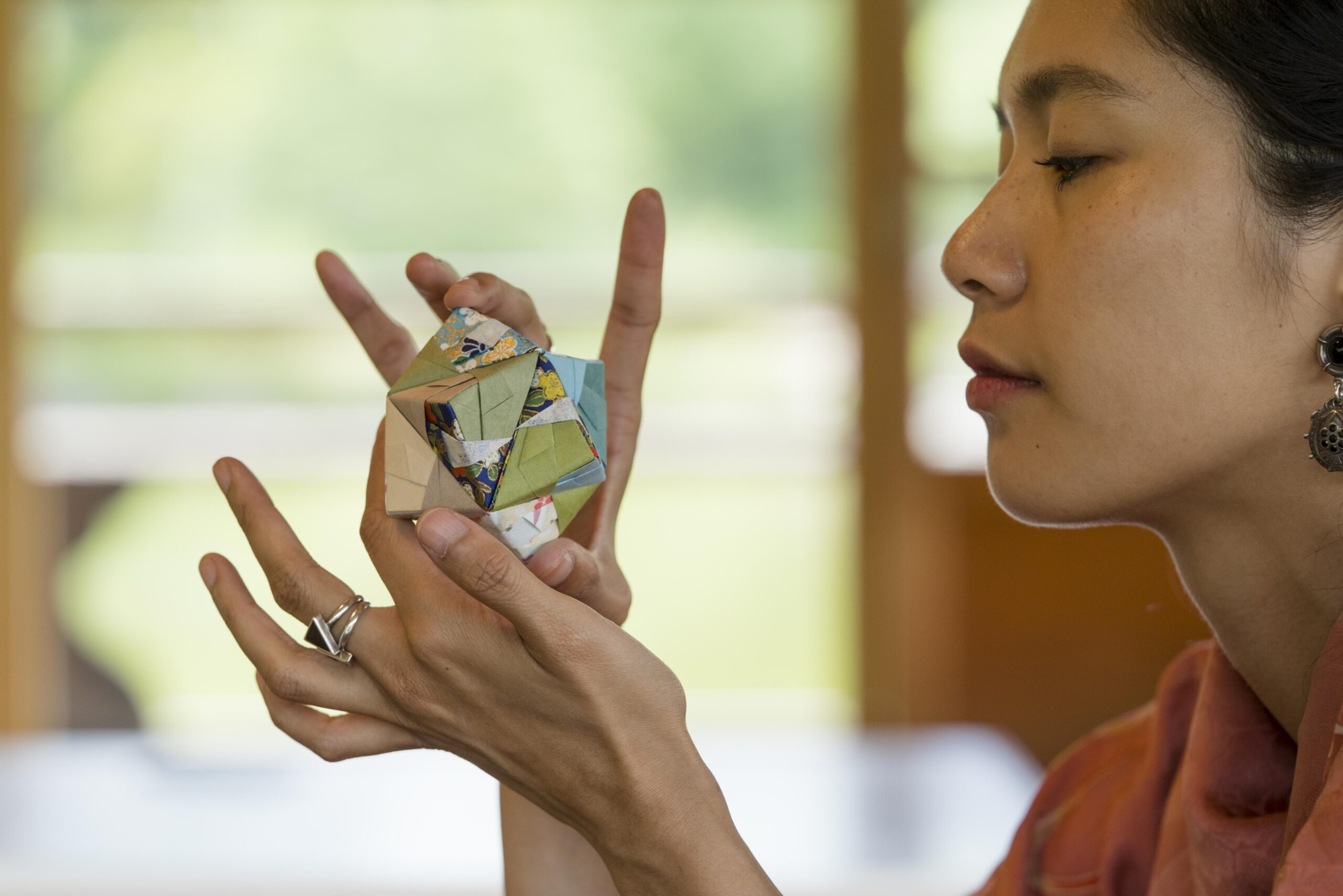 Woman's hands carefully holding a colorful origami creation.