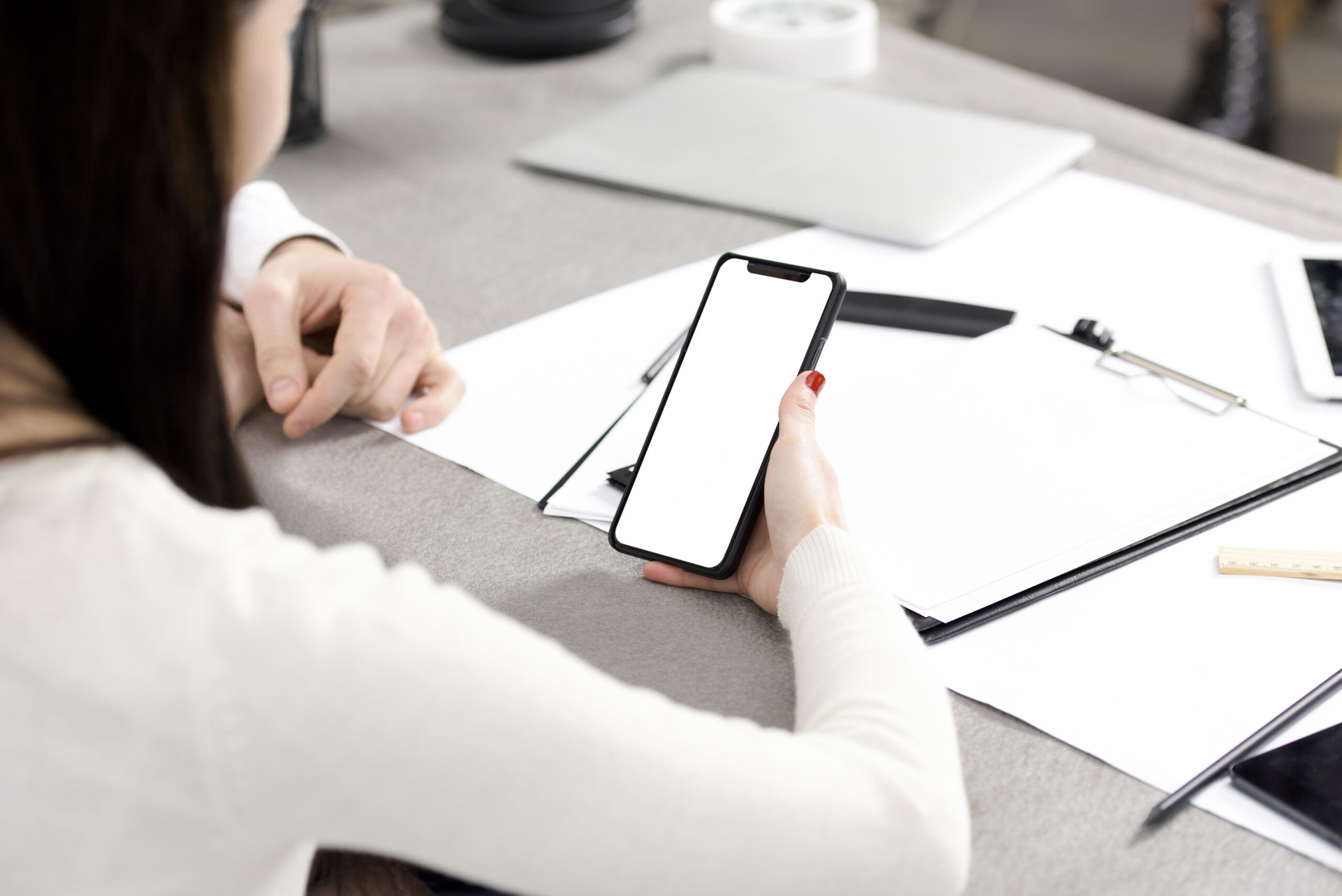 Woman reviewing a smartphone with a blank screen, possibly checking an informal will.