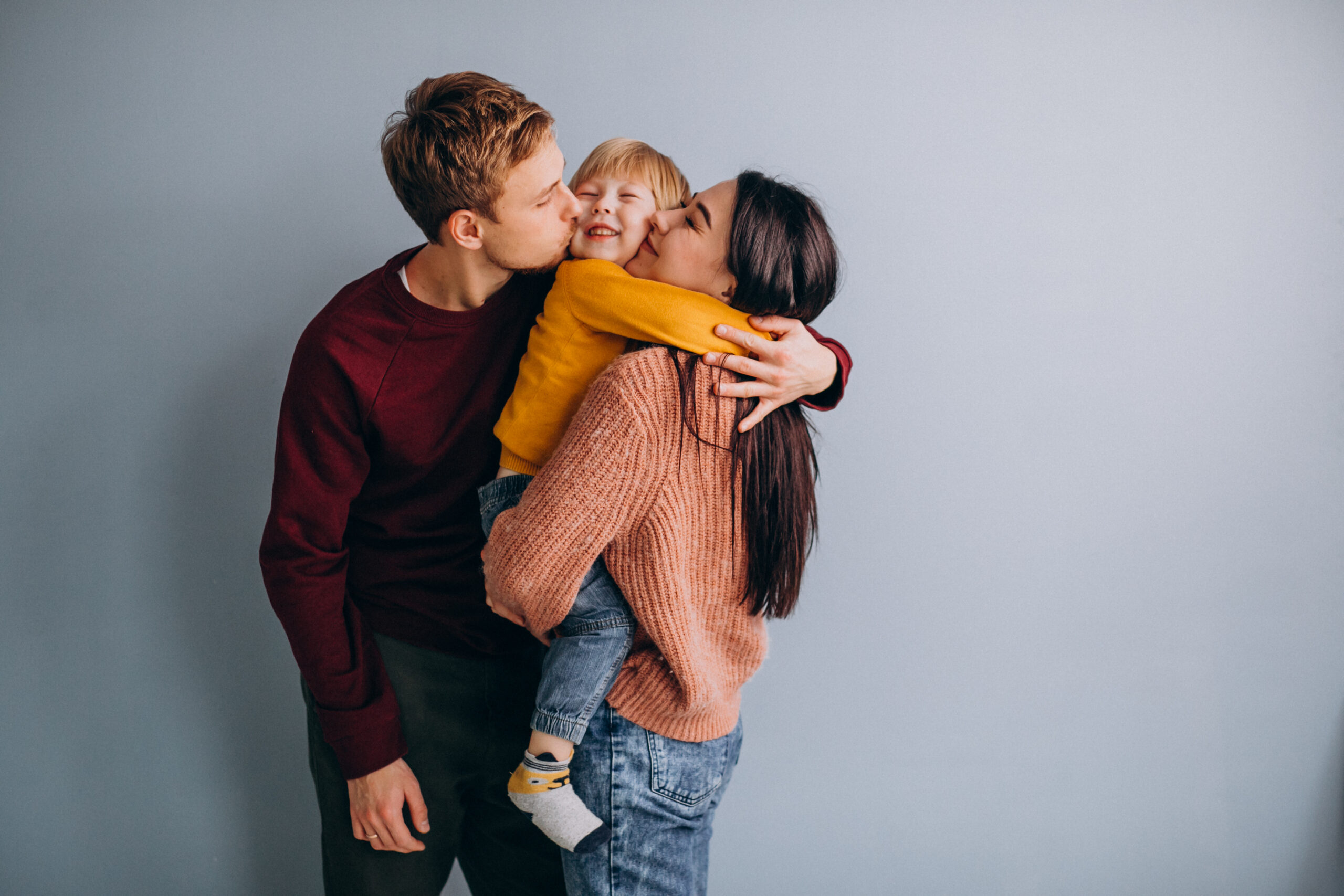 Happy family of three embracing—parents and child.