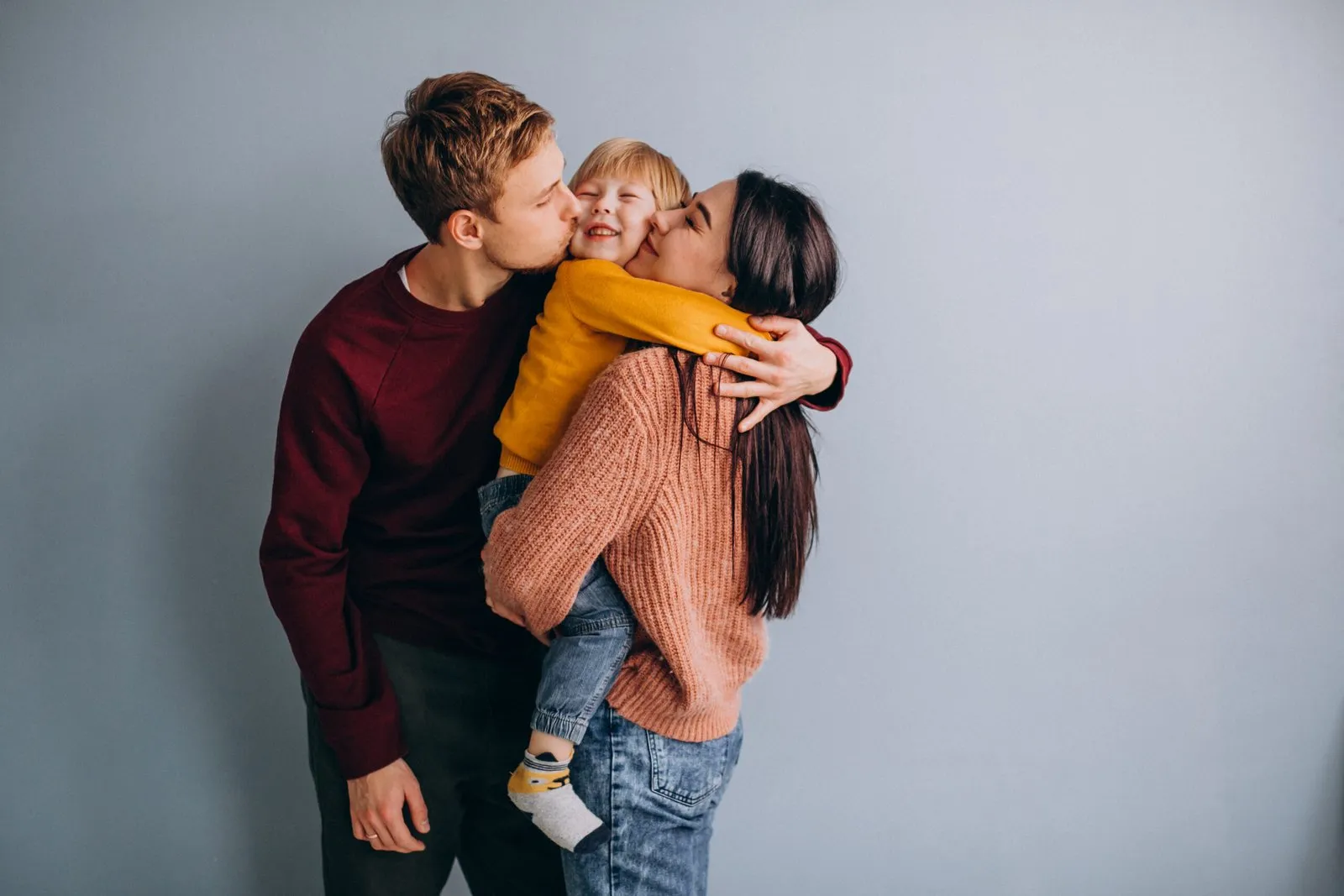 Happy family of three embracing—parents and child.