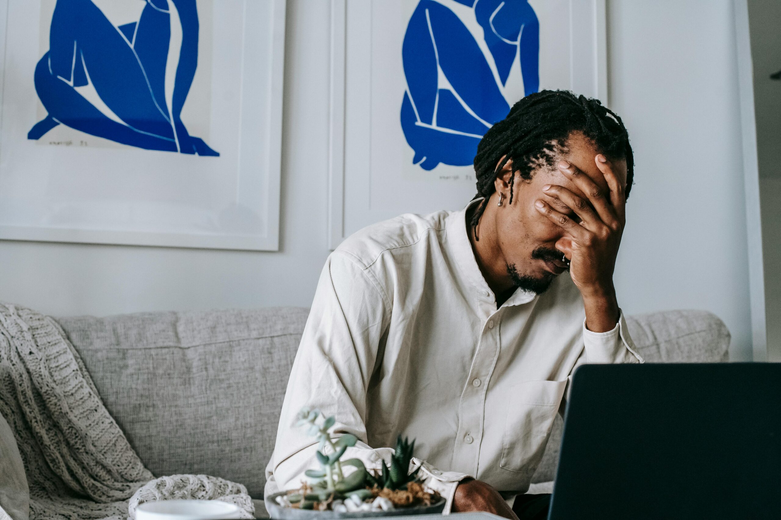 Stressed man covering his face while working on laptop. Contesting a will can be stressful.