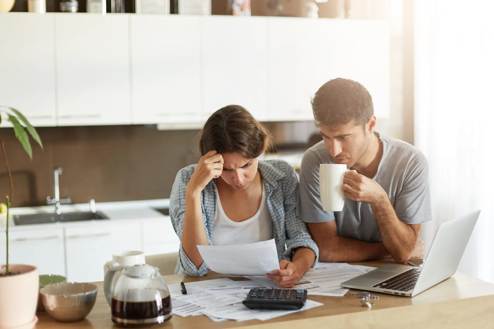Couple reviewing documents at kitchen table with worried expressions