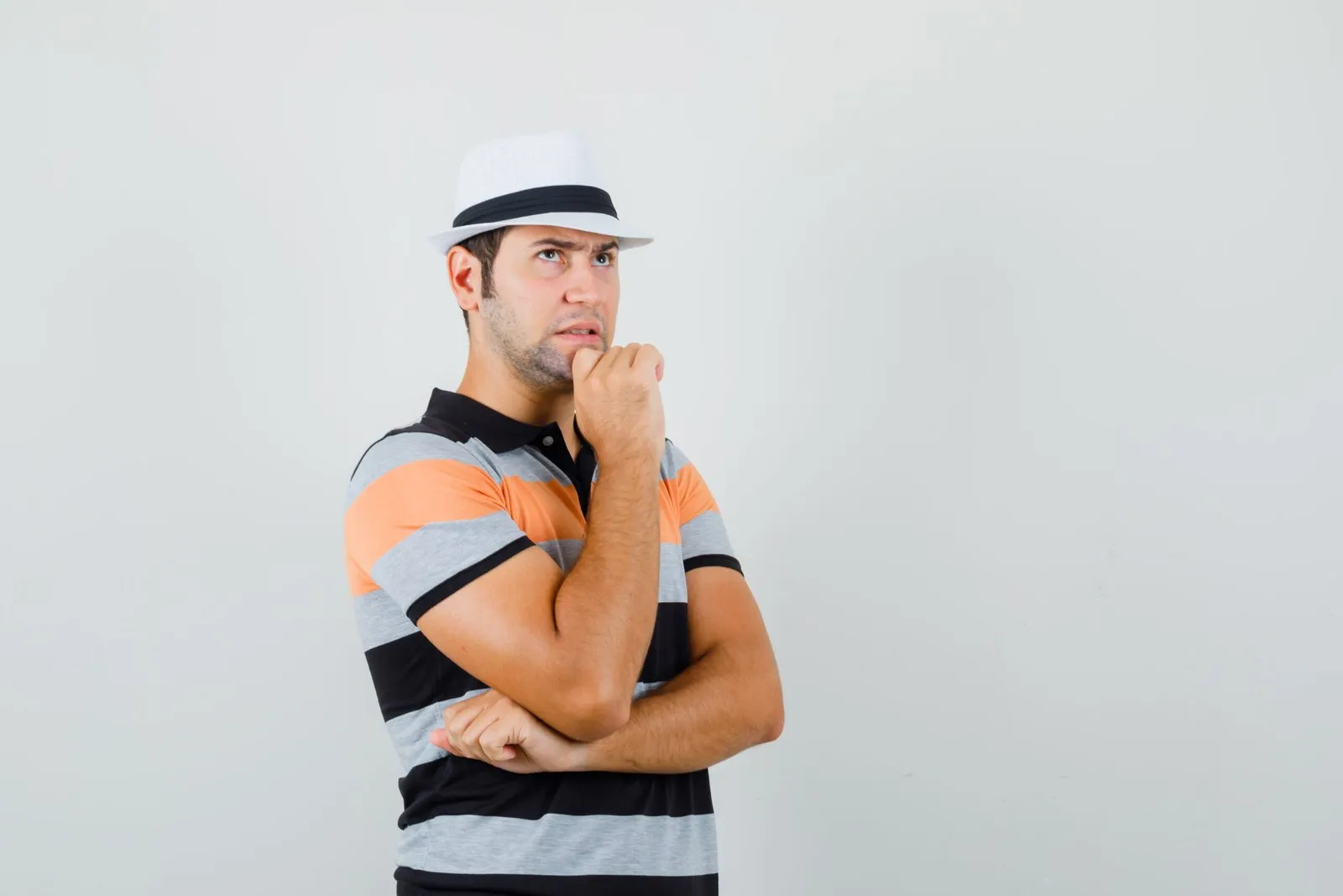 Man in striped shirt and hat, looking thoughtful.