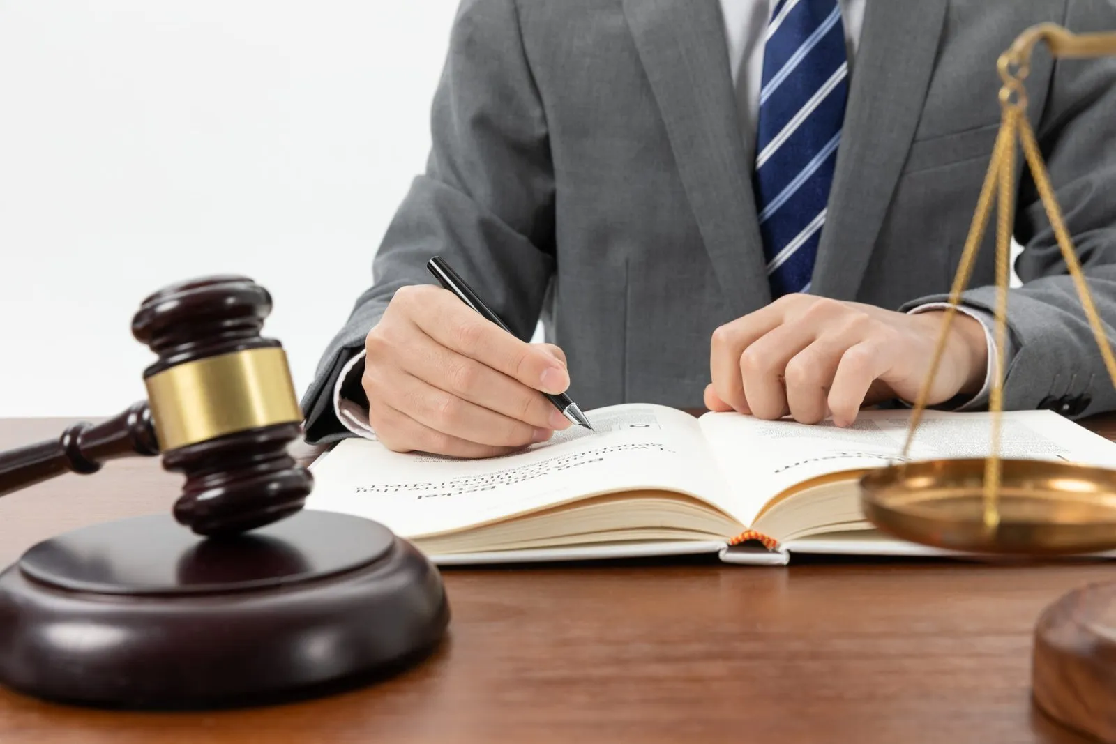 Lawyer writing in a legal book next to a gavel