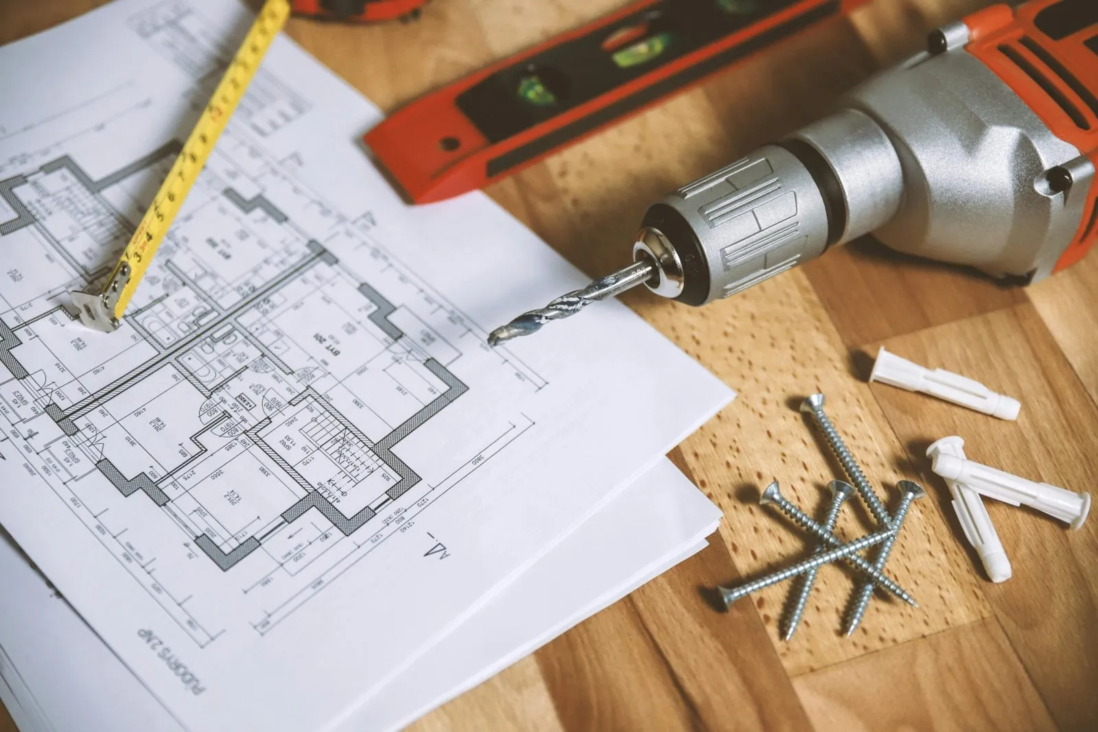Tools and blueprints for home renovations, including a drill, screws, and a tape measure.