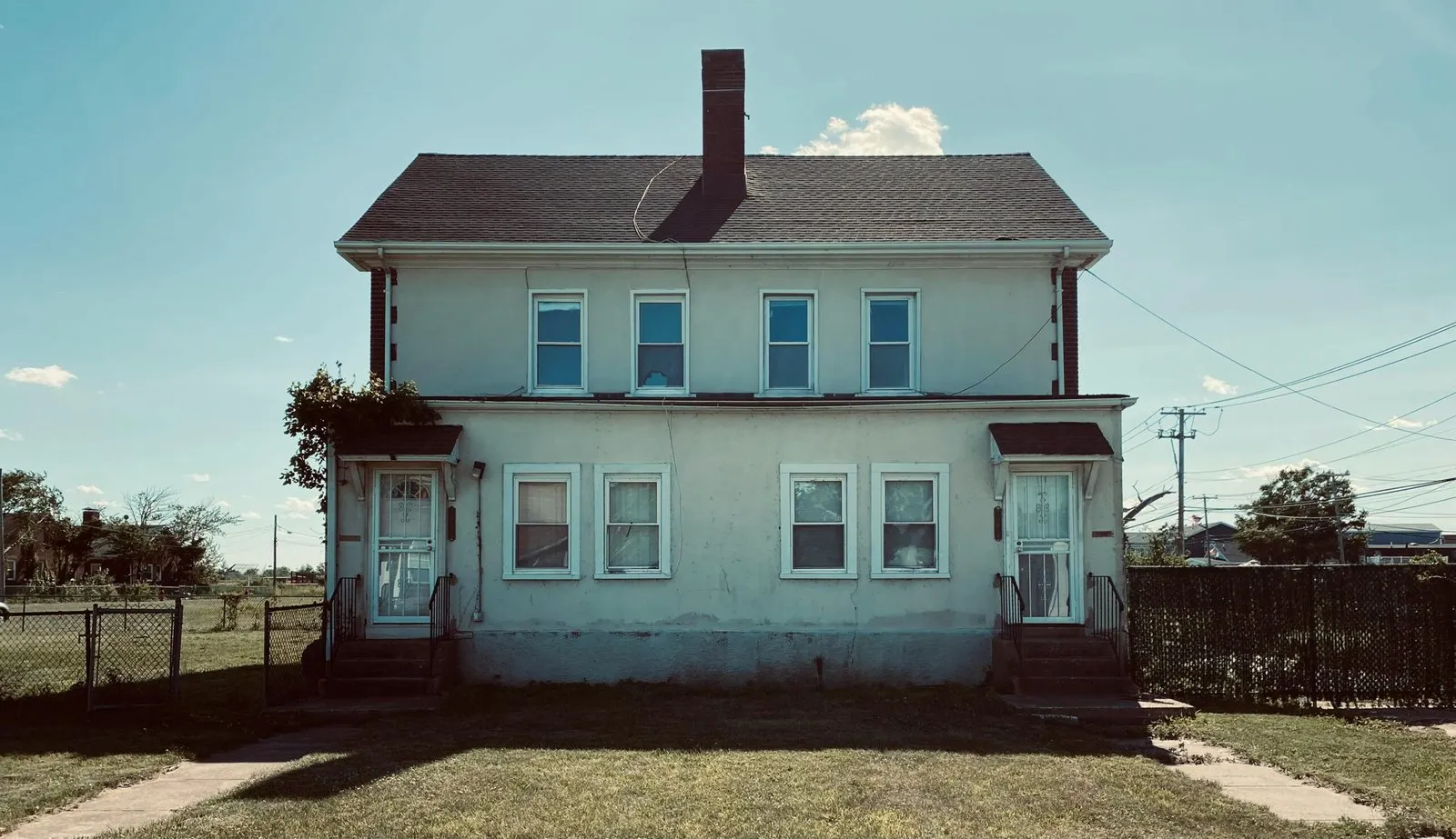 Older duplex home with two front doors and six windows. Needs renovation.