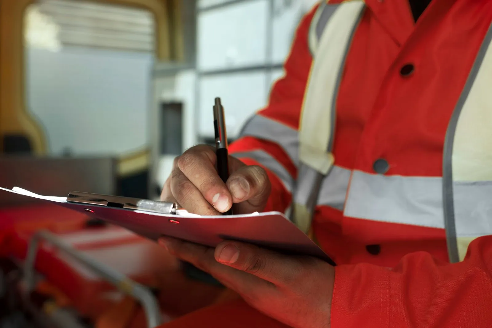 Inspector in orange safety gear reviewing paperwork indoors