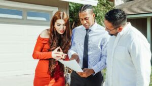 Real estate agents and client reviewing documents in front of a house