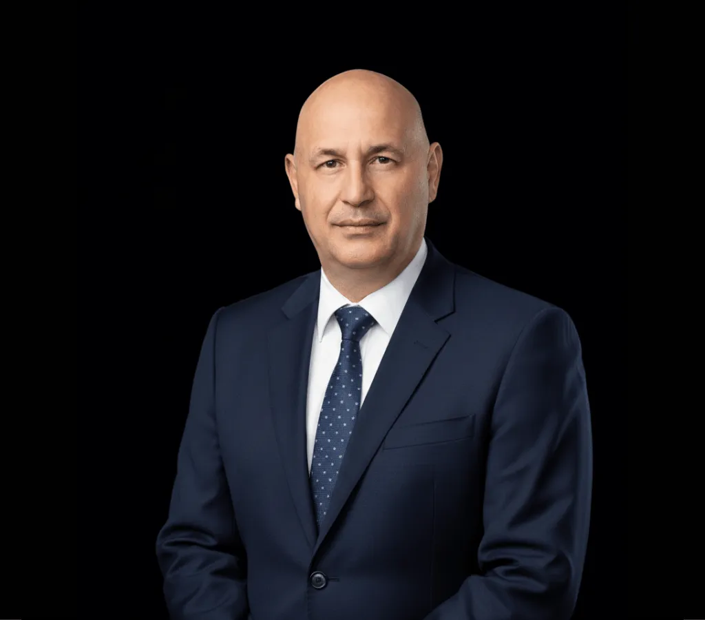 Professional headshot of a bald man in a navy suit and patterned tie.