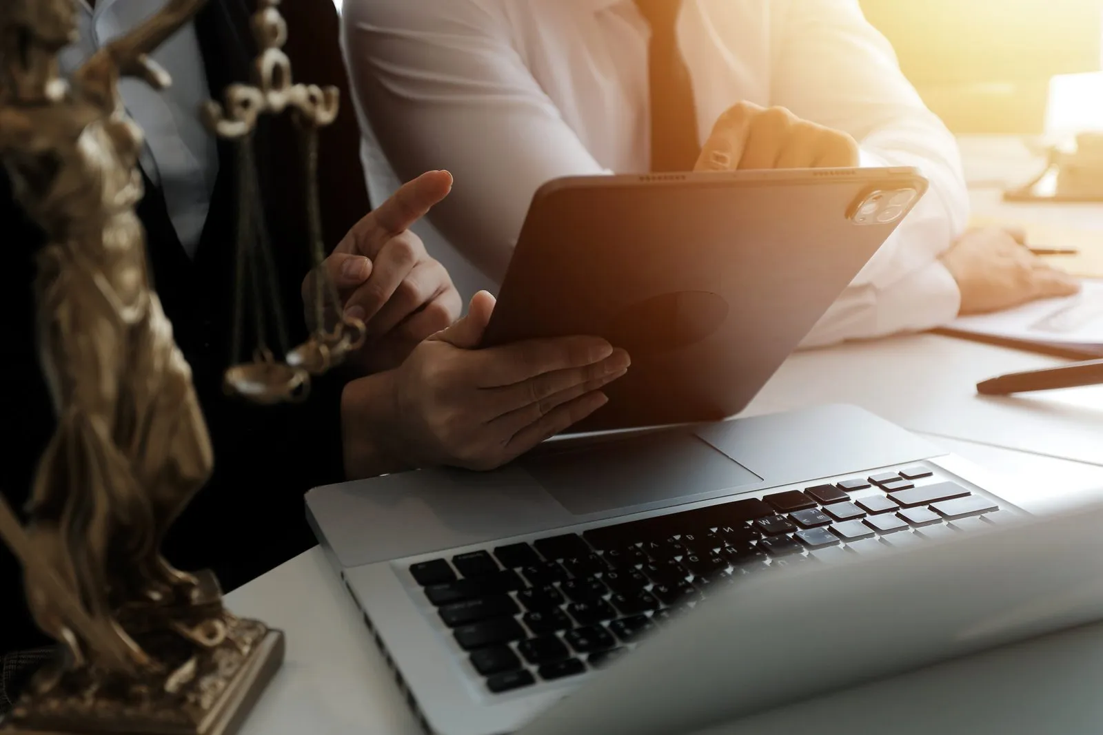Lawyers reviewing financial data on a tablet and laptop. Legal and financial consultation.
