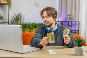 Content creator counting money while looking at a laptop, possibly related to taxes on gifts and products.