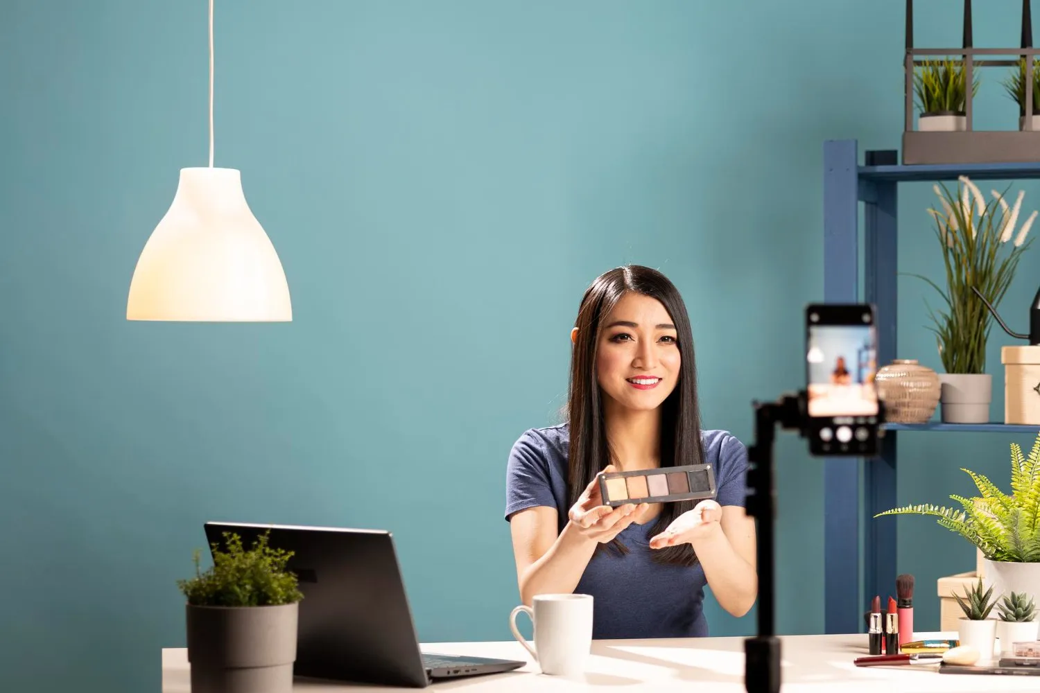 Asian woman reviewing makeup palette for a video blog. Creator content.