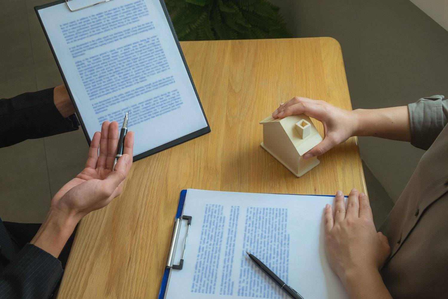 Real estate contract review with a house model on the table.