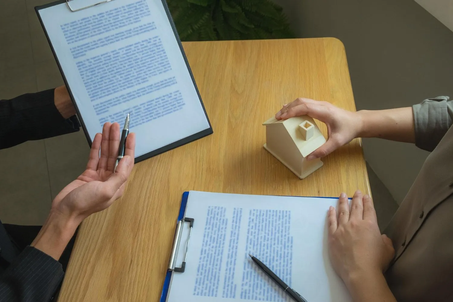 Real estate contract review with a house model on the table.
