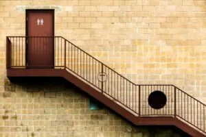 Exterior staircase leading to a restroom door on a brick building.