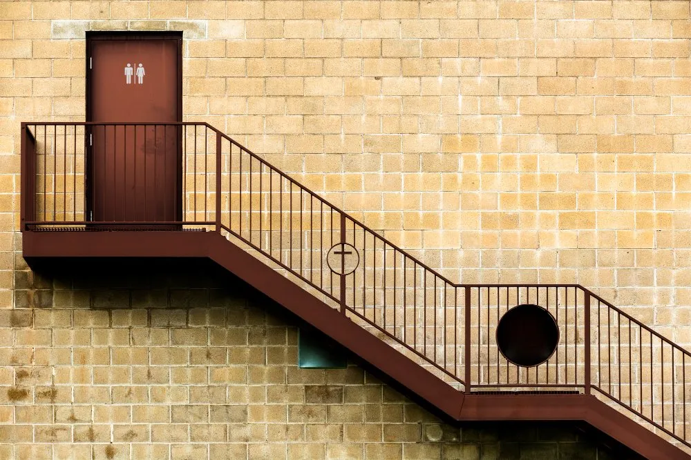 Exterior staircase leading to a restroom door on a brick building.