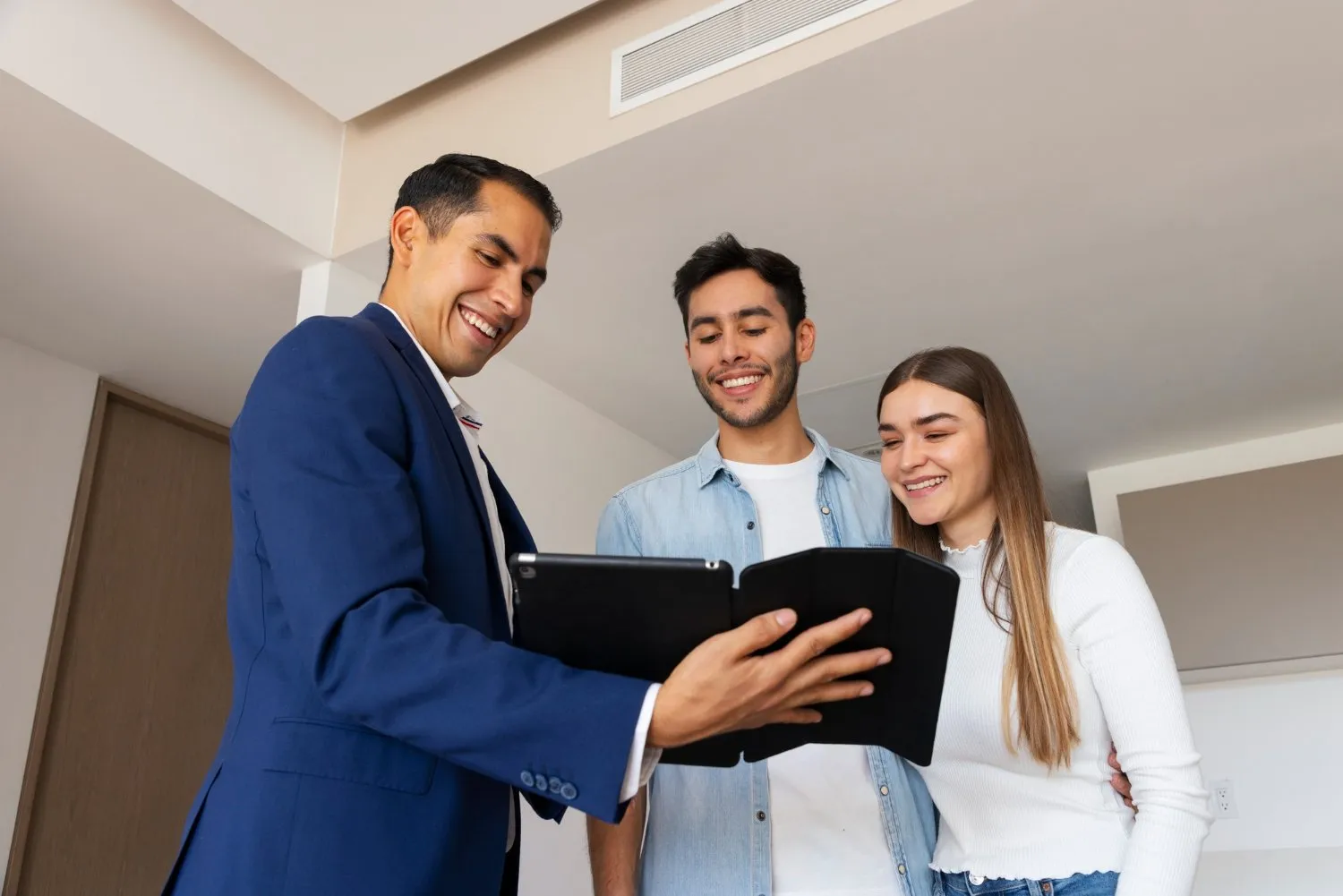 Real estate agent showing documents to a young couple in a modern apartment.
