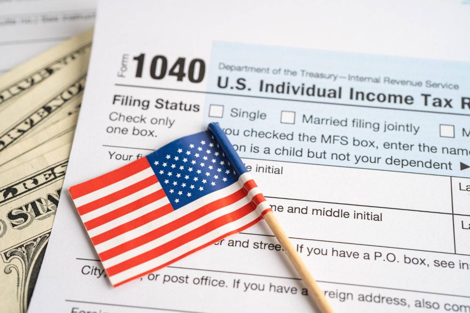 US 1040 tax form with American flag and cash. Filing taxes.