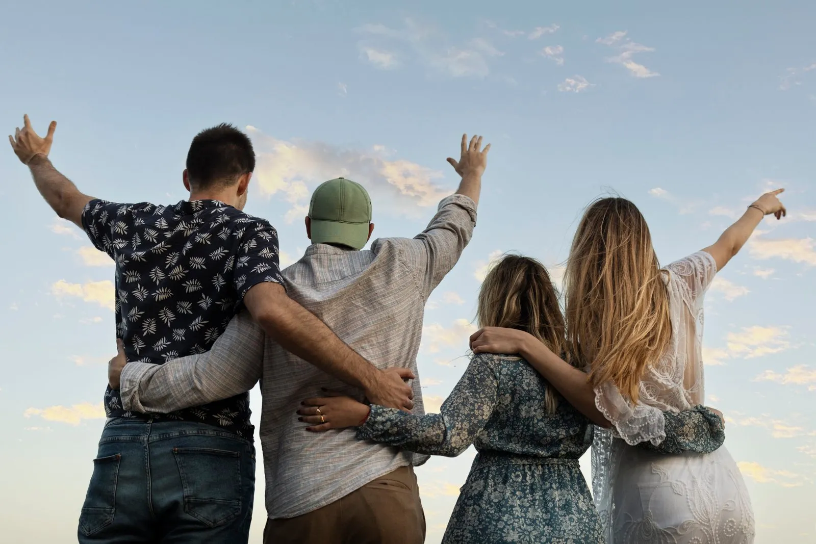 Four friends embrace, arms around each other, looking at the horizon. Friendship and family support.