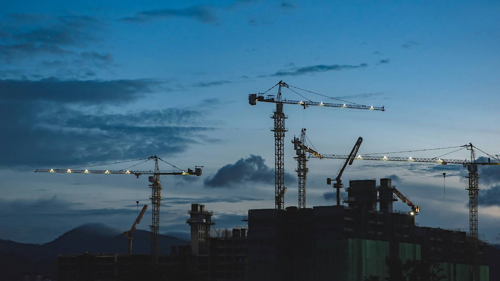 Construction site at dusk with multiple cranes, relevant to tax implications on development projects.
