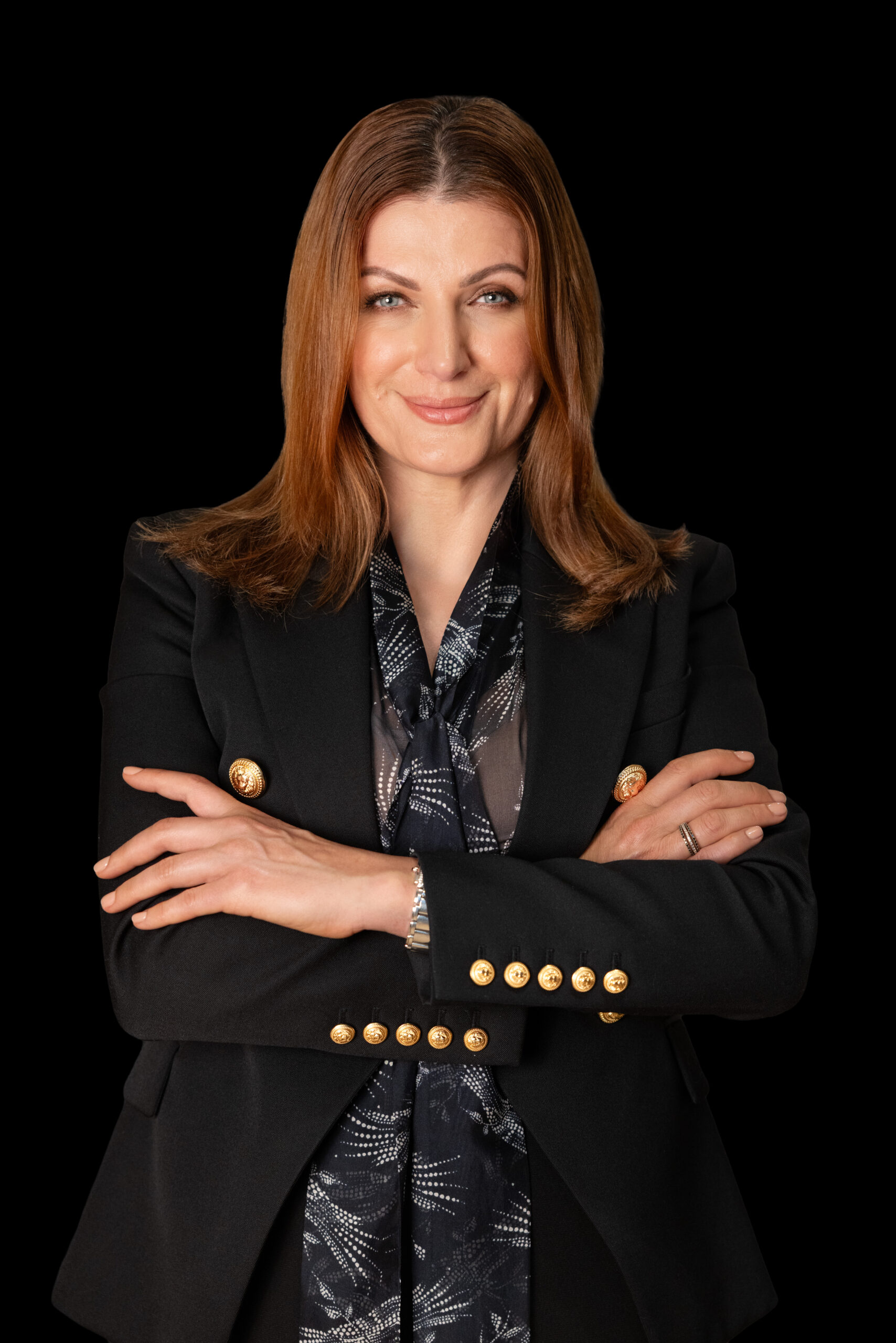 Sonia Jacob, a confident woman in a black blazer, smiles with arms crossed.